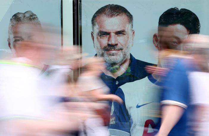 Fans of Tottenham Hotspur walk past a giant picture of Ange Postecoglou,