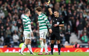 Referee Nick Walsh shows a yellow card to Arne Engels