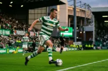 Celtic midfielder in green hooped kit controlling football at Celtic Park stadium