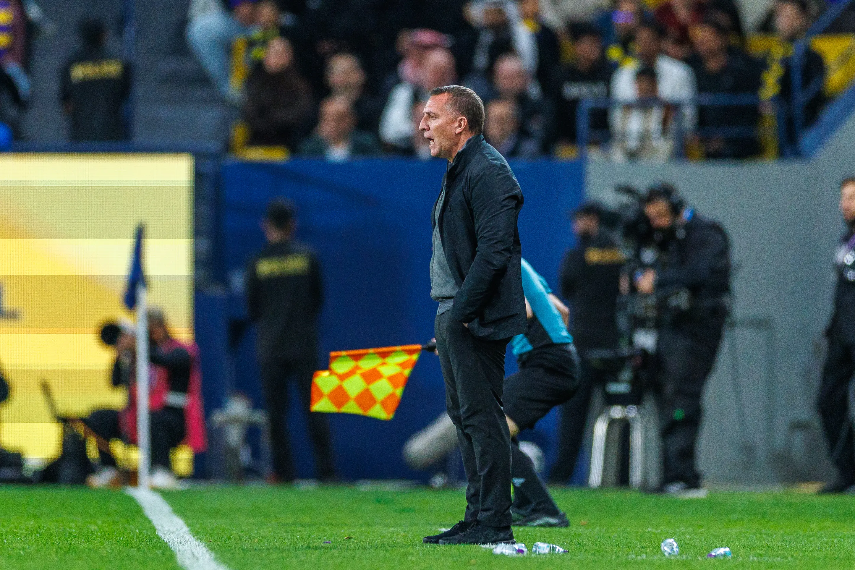 Brendan Rodgers in a black jacket on the sidelines during a football match.
