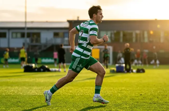 Young Celtic striker training on pitch in green hooped jersey during golden hour workout session