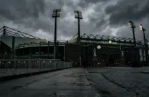 Celtic Park stadium exterior under moody grey skies symbolizing management departure and transition