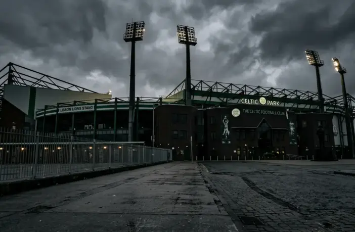 Celtic Park stadium exterior under moody grey skies symbolizing management departure and transition