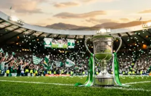 Celtic FC championship trophy with green and white ribbons in packed stadium at sunset