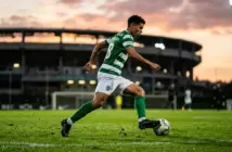 Young midfielder in green and white jersey controlling football during golden hour training session