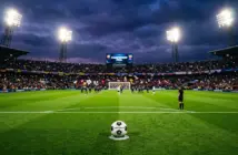 Football on penalty spot under stadium floodlights in dramatic title-deciding match atmosphere