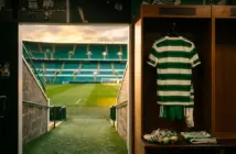 Celtic FC locker room with hoops jersey and view of Parkhead pitch symbolizing player transfers