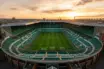 Celtic Park stadium bathed in golden light, showing empty stands and pitch from elevated view