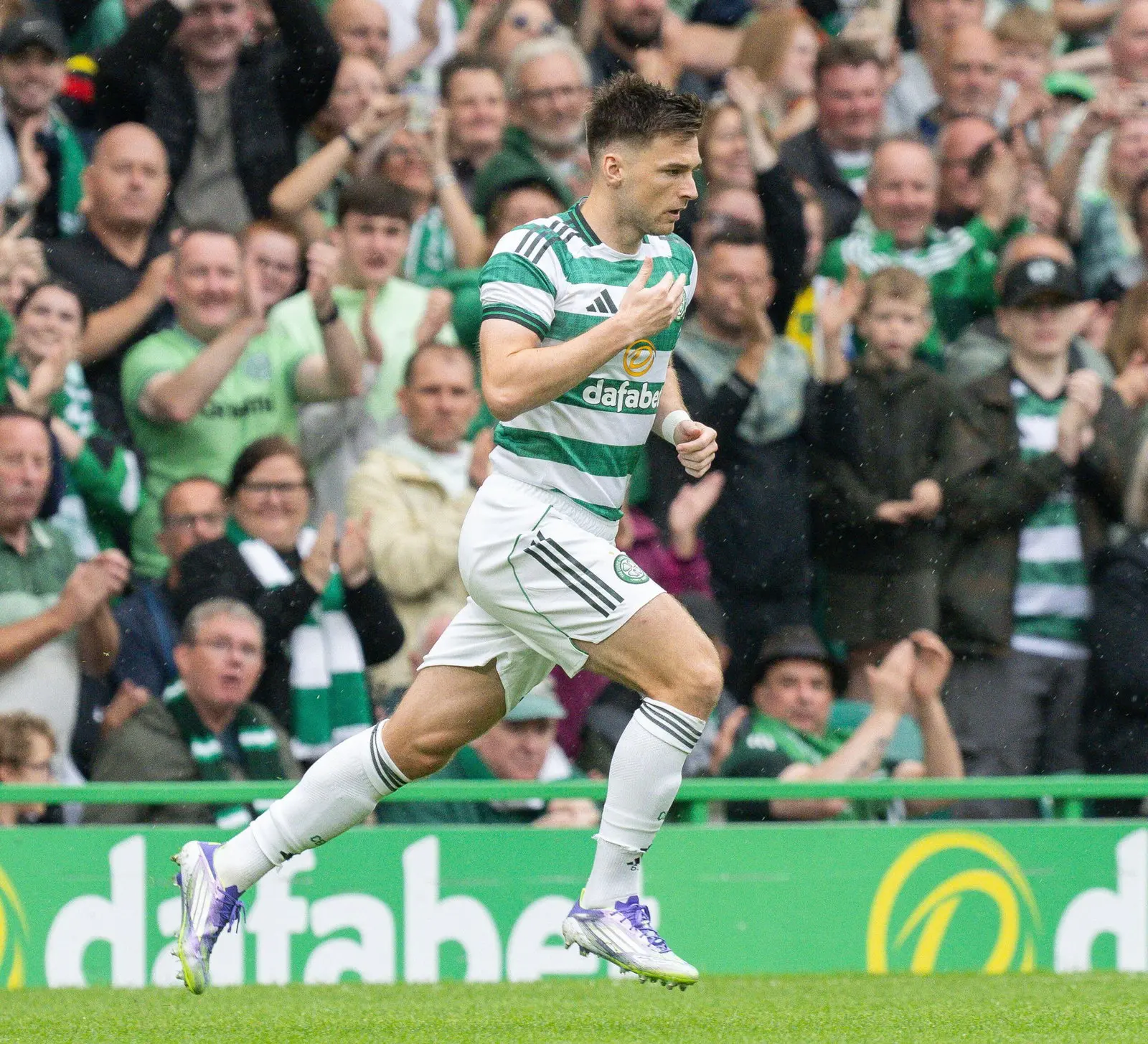 Kieran Tierney celebrating during a Celtic match with fans cheering.