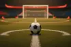 Empty floodlit football pitch with ball on centre spot, gold-hour stadium lighting, red and white accent colours.