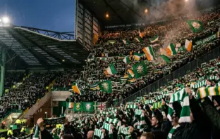 Celtic supporters holding scarves aloft in unity at Celtic Park stadium