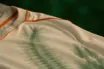 Off-white football kit with green tie-dye hoops and orange trim detail in soft natural lighting