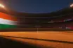 Floodlit stadium at sunset with packed stands, golden-hour pitch lighting, and dramatic shadows during World Cup knockout match.