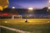 Empty floodlit stadium pitch with centre circle ball, blue and red atmospheric lighting, dusk lighting.