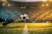 Floodlit stadium with turquoise and yellow-clad supporters; football mid-flight in dramatic golden-hour light.