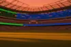 Empty floodlit stadium at dusk with Czech blue and Mexican green accent lighting, cinematic shadows across pitch.