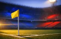 Empty stadium corner with blue-and-red flag-coloured floodlighting, corner flag sharp in foreground, golden dusk light across tiered seating.