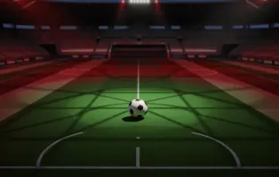 Aerial stadium view of floodlit pitch with match ball on centre circle, red-green colour accent lighting, evening kick-off atmosphere.