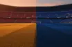Floodlit stadium pitch at golden hour with packed stands, divided lighting creating dramatic shadows across the field.