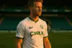 Celtic footballer in hooped jersey standing confidently at Parkhead stadium