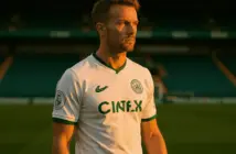 Celtic footballer in hooped jersey standing confidently at Parkhead stadium