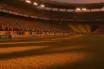 Floodlit stadium at dusk with packed stands and dramatic shadows; Mexico and Ecuador national colours in crowd atmosphere.