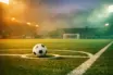 Floodlit football pitch at dusk with match ball on centre spot, colour-graded in Mexico and South Africa national colours, low corner-angle shot.