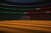 Floodlit football stadium at dusk with green and red crowd sections, dramatic shadow patterns on empty pitch.