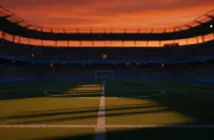 Empty floodlit stadium pitch with dramatic shadows, Dutch orange and Swedish blue atmospheric lighting at dusk.