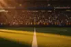 Floodlit World Cup 2026 stadium at golden hour with packed stands and dramatic pitch shadows.