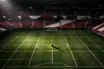 Aerial view of floodlit football stadium with maroon-and-white colour scheme, ball on centre spot, empty stands with bunting