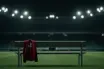 Empty manager's dugout with Scotland jacket under stadium lights at night