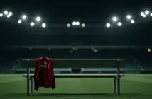 Empty manager's dugout with Scotland jacket under stadium lights at night