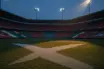 Empty floodlit stadium at dusk with Scottish blue-white and Moroccan red-green colour palette, dramatic shadows, rain-wet pitch.