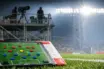 Tactical pitch diagram on analyst desk with stadium gantry and bright floodlights in background; Group Stage match preview setup