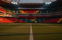 Modern floodlit football stadium at dusk with geometric pitch markings, red and green crowd sections, dramatic shadows.