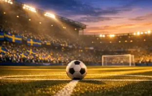 Floodlit stadium pitch at golden hour with blue-yellow draped stands and football on centre spot.