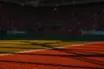 Floodlit World Cup stadium pitch with red and white colour tones, golden-hour lighting, packed stands in background.