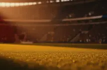 Floodlit football stadium pitch at golden hour with dramatic shadows and packed stands, warm cinematic lighting