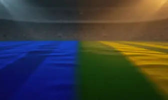 Empty floodlit stadium pitch at golden-hour kick-off with blue and green-yellow shadow patterns, no players