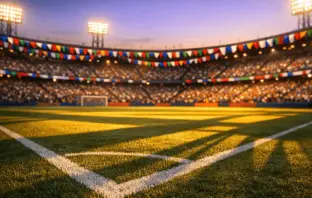 Floodlit stadium with colourful bunting, packed stands, and shadow-dappled pitch at golden hour.
