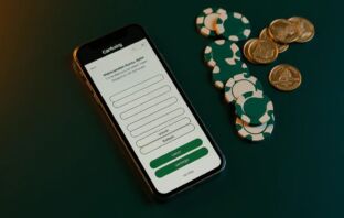 Smartphone with Interac e-Transfer wireframe screen surrounded by casino chips and Canadian coins on a green surface