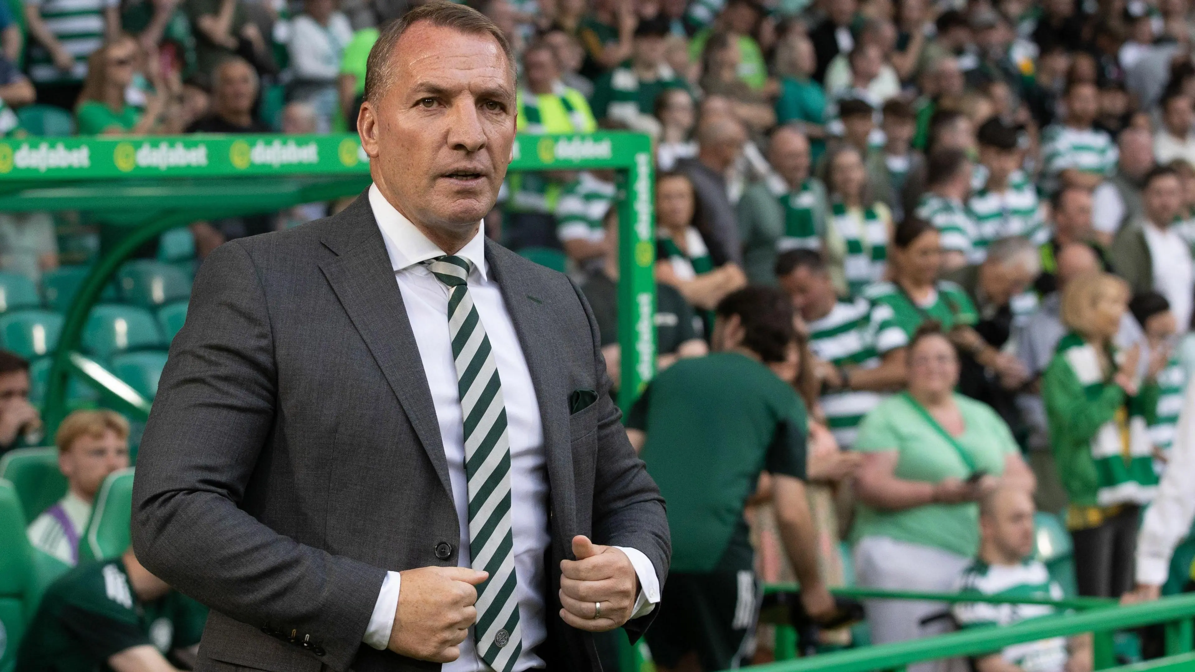 Brendan Rodgers in a grey suit with a Celtic tie on the sideline during a match.
