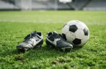 Football boots and ball on green pitch representing striker recruitment opportunity