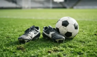 Football boots and ball on green pitch representing striker recruitment opportunity