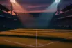 Empty floodlit football pitch at dusk with stadium stands in shadow, dramatic lighting creating geometric patterns.