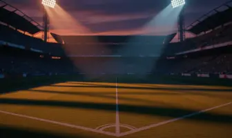Empty floodlit football pitch at dusk with stadium stands in shadow, dramatic lighting creating geometric patterns.