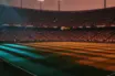 Floodlit quarter-final stadium at dusk with dramatic shadow patterns, French and Moroccan colour palette reflected in packed stands.