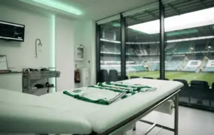 Modern football medical room with green kit awaiting player examination before transfer signing