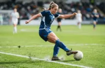 Women's football defender in action on green pitch with white markings